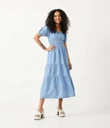 Vestido midi de jeans celeste, con escote cuadrado con lazo, mangas cortas abullonadas, cintura elastizada y falda escalonada con volados.