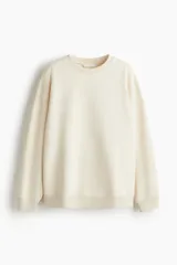 Buzo de tejido liso color crema, con cuello redondo acanalado, hombros caídos y puños y bajo acanalados.