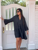 Vestido corto negro de lino, con escote en V, botones frontales y mangas largas acampanadas con volados.