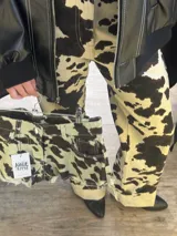 Pantalón de tiro alto color beige con estampado de manchas de vaca en marrón oscuro.