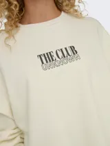 Sudadera color crema de algodón con cuello redondo, mangas largas con hombros caídos, puños y bajo elásticos. Estampado frontal con la frase "The Club Unknown".