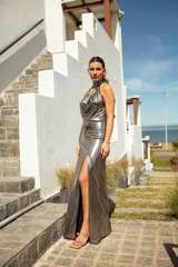Vestido largo azul metalizado con cuello halter, buche pronunciado y tajo en la falda.