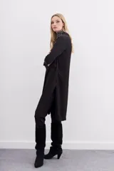 Kimono largo hasta la rodilla, color negro con estampado jacquard. Tiene solapa, botón frontal, tajos laterales y bolsillos ojal con solapa en el frente.