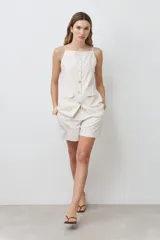 Chaleco color beige con botones de nácar, sin mangas y con bolsillos frontales.