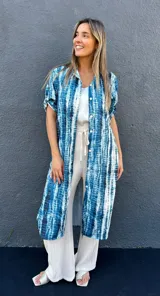 Sobrecamisa o vestido largo con estampado tie-dye en tonos azules y blancos, con cuello camisero, mangas cortas y cierre frontal con botones.