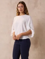 Blusa de gasa color blanco con estampado de hojas verdes, de mangas 3/4 abullonadas con puños elásticos.