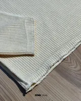 Buzo color crema de lana premium con textura acanalada y costuras expuestas.