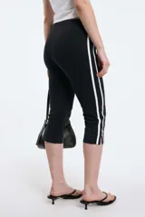 Calzas capri negras con cintura elástica y una raya blanca vertical a lo largo de la pierna.