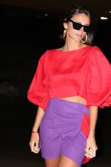Falda violeta de lino, corte mini con diseño cruzado y lazo lateral rojo.