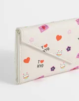 Billetera formato fichero de cuerina color crudo, con estampado de gatos de la suerte, corazones y flores. Tiene solapa con broche a presión, compartimentos para tarjetas y billetes.