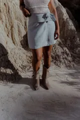 Bota texana de cuero color beige con punta marcada, caña media y flecos decorativos en el lateral externo.