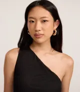 Vestido negro de largo midi, confeccionado en tul con un solo hombro descubierto y fruncido lateral que genera un efecto drapeado.