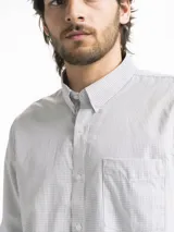 Camisa celeste y blanca a rayas verticales, de manga larga y corte clásico. Tiene cuello abotonado y bolsillo en el pecho.