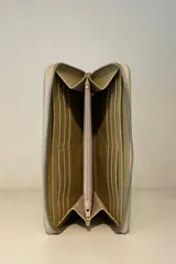 Billetera de charol color rojo con cierre perimetral y logo metálico plateado en el frente.