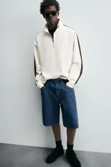 Sudadera color crudo de corte relaxed fit, con cuello alto con cremallera y mangas largas con banda marrón a contraste.