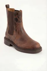 Bota tipo Chelsea de cuero legítimo en color marrón con acabado texturizado. Presenta paneles elásticos laterales al tono, tirador trasero para facilitar el calce y suela de goma gruesa con vira pespunteada.