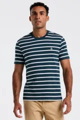 Remera de manga corta, cuello redondo, color verde azulado oscuro con rayas horizontales blancas. Presenta un pequeño logo bordado en el pecho.