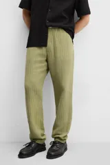 Pantalón verde oliva de corte relaxed fit, confeccionado en tejido de algodón con textura. Tiene cintura elástica ajustable con cordón, bolsillos frontales y un bolsillo trasero de parche.