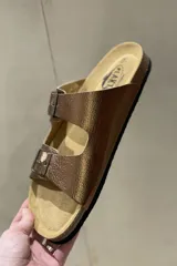 Sandalias blancas de cuero con doble tira y hebillas metálicas ajustables. Suela anatómica de corcho y goma.