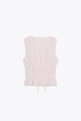 Top amarillo con estampado de cuadros vichy blancos, escote en pico, sin mangas, con detalle de elásticos en la cintura y cierre frontal con lazadas.