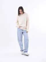 Canguro de tejido punto color crudo, con capucha y cordones ajustables. Presenta puños y cintura acanalados.