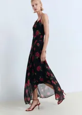 Vestido largo negro con estampado de rosas rojas, escote asimétrico con drapeado y bretel fino en un hombro.