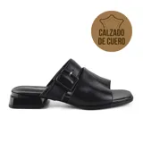 Sandalia de cuero color visón, con tira ancha sobre el empeine y tira con hebilla ajustable en el tobillo. Tiene taco bajo cuadrado y suela de goma.