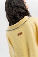 Buzo amarillo de algodón con cuello polo, mangas largas y bordado de un sello con motivos marinos.
