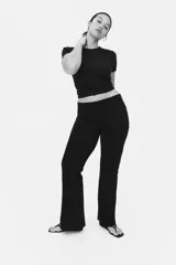 Pantalón negro de punto suave, con cintura ancha plegable y corte acampanado.