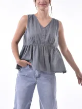 Blusa blanca sin mangas con escote en V y cierre frontal con botones.