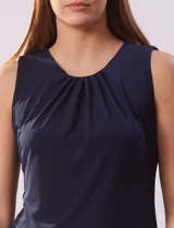 Blusa sin mangas color amarillo, con cuello redondo con frunces delanteros y abertura con botón en la espalda.