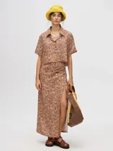 Vestido largo color marrón con estampado floral, escote en V, tirantes finos y abertura lateral.