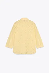 Camisa amarilla de cuello solapa y manga larga acabada en puño. Detalle de bordados perforados a tono. Cierre frontal con botones ocultos por solapa.