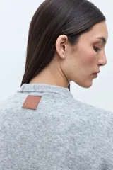 Ruana de tejido de punto color rosa melange, sin mangas y con cuello redondo.