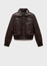 Chaqueta bomber de cuero color marrón oscuro con cuello camisero y cierre frontal con cremallera y botones a presión. Tiene terminaciones elásticas en puños y cintura, y dos bolsillos laterales.