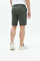 Bermuda de gabardina color verde militar, con bolsillos laterales y traseros, cierre con cremallera y botón, y trabillas para cinturón.