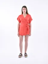 Vestido corto cruzado color rojo coral, con escote en V, mangas cortas tipo mariposa y lazo ajustable en la cintura.