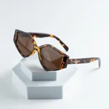 Lentes de sol con montura geométrica carey y lentes marrones. El logo de la marca está impreso en la patilla.