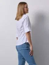 Camisa blanca de algodón marca Zac & Rachel, con cuello con solapa, escote en V, apertura central con botones metálicos, bolsillos delanteros, mangas 3/4 regulables y laterales en tejido modal.