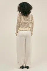 Pantalón color crema de lino y tencel, con bolsillos laterales, cintura elástica y cordón ajustable. Detalle regulable en el tobillo.