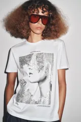 Camiseta blanca de corte recto y manga corta, con estampado frontal de una fotografía en blanco y negro y texto "Amsterdam 74".