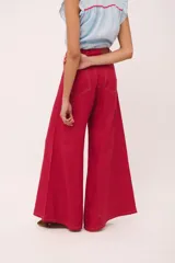 Pantalón de tiro alto, corte ancho y largo, color beige claro con finas rayas verticales en tono oscuro. Presenta cierre frontal con botón y bolsillos tipo jean.