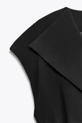 Chaleco negro cruzado con cuello solapa y sin mangas. Incluye cinturón de la misma tela para ajustar a la cintura.