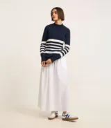 Blusa alargada de punto color azul marino con rayas horizontales blancas, cuello alto y mangas largas con botones en los puños.