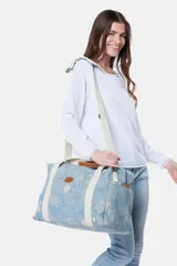 Bolso tipo tote de lona color celeste con estampado de hojas en blanco, detalles en cuero marrón y correa de hombro de lona color crudo.