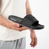 Chanclas negras con la palabra "GAIN" en relieve en la tira superior y "AMBITION" en el lateral de la suela.