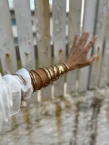 Brazalete rígido dorado con textura irregular.