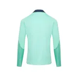 Remera deportiva Nike Dri-FIT Strike color verde agua con cuello alto azul marino y cierre de un cuarto. Logo de Nike estampado en blanco en el pecho.