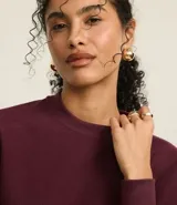 Sweater color borgoña de algodón con poliéster, cuello redondo y mangas largas con puños acanalados.