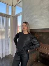 Blusa negra brillante de mangas largas abullonadas.